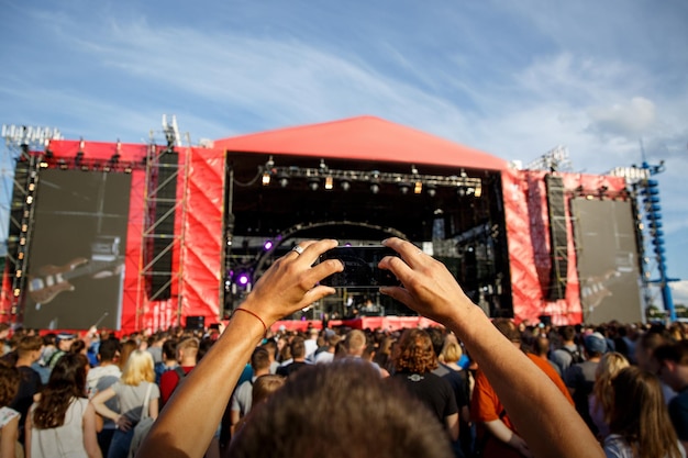 Uomo che tiene gli smartphone in mano e fotografa il festival di concerti di musica all'aperto d'estate