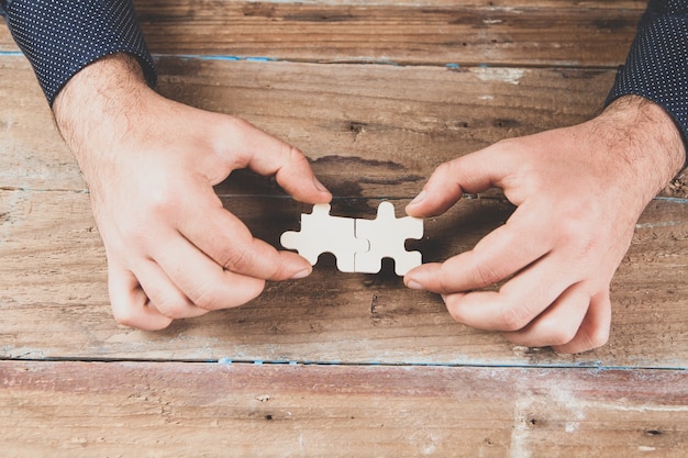 Uomo che tiene i pezzi del puzzle sulla scena in legno