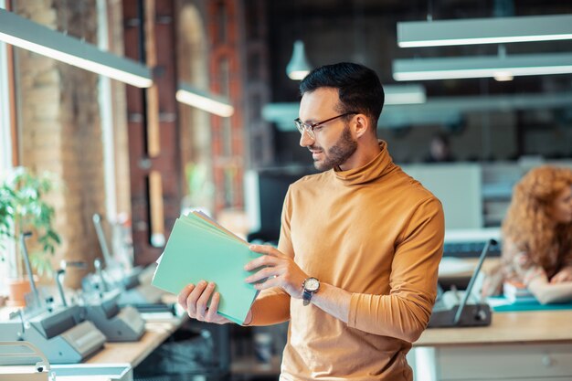 Uomo che tiene i taccuini. Uomo barbuto che tiene i taccuini che lavorano nella società editrice