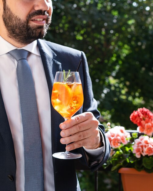 Uomo che tiene il bicchiere con aperol italiano spritz, cocktail alcolici