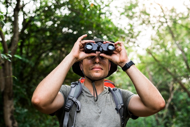 Uomo che tiene il binocolo nella foresta