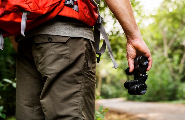 Uomo che tiene il binocolo nella foresta