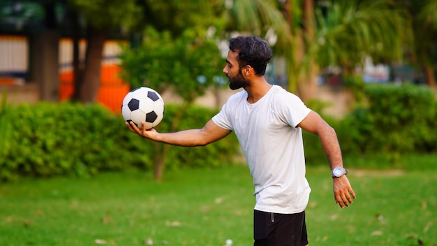 Uomo che tiene il calcio nel parco verde