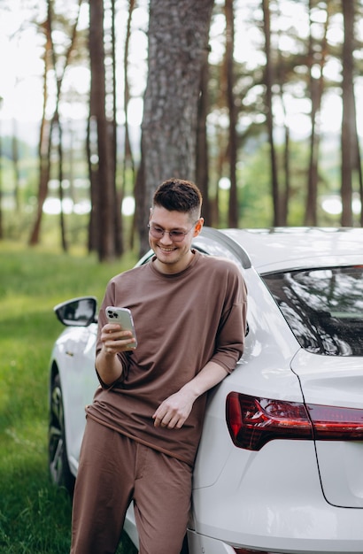 Uomo che tiene il cavo di ricarica per auto elettrica nel parcheggio all'aperto e collegherà l'auto alla stazione di ricarica nel parcheggio vicino al centro commerciale