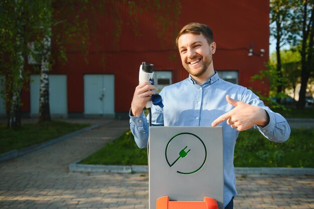 Uomo che tiene il cavo di ricarica per auto elettrica