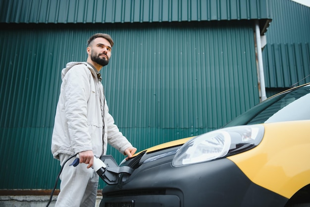 Uomo che tiene il connettore di alimentazione per auto elettrica