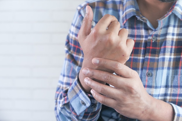 Uomo che tiene il polso e che soffre di dolore in mano con copia spazio