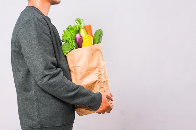 Uomo che tiene la borsa della spesa con verdure per uno stile di vita sano concept