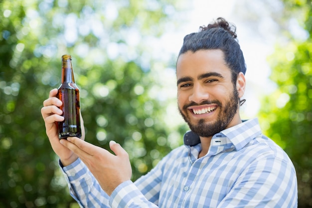 Uomo che tiene la bottiglia di birra nel parco