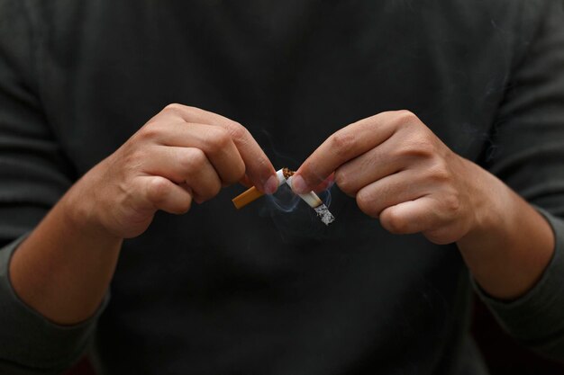 Uomo che tiene la sigaretta rotta nelle mani Smettere di fumare sigarette concetto Concetto di campagna per non fumare