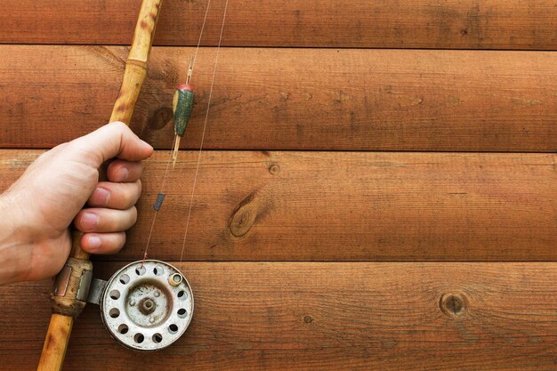 Uomo che tiene la vecchia canna da pesca in mano