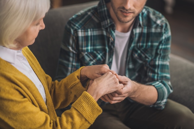 Uomo che tiene le mani della sua mamma con amore