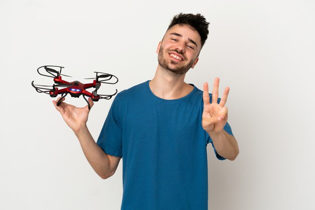 Uomo che tiene un drone isolato su sfondo bianco felice e conta tre con le dita