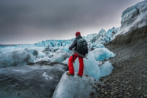 Uomo che tiene un treppiede contemplando gli iceberg