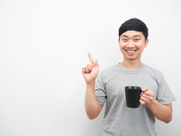 Uomo che tiene una tazza di caffè con sorridente e punta il dito sullo spazio della copia