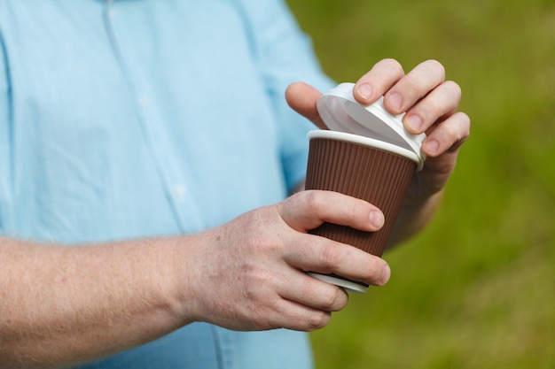 Uomo che tiene una tazza di caffè di carta