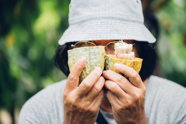 Uomo che tira fuori i fagioli dal baccello di cacao aperto