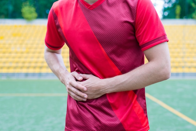 Uomo che tocca il lato destro sullo sfondo dello stadio