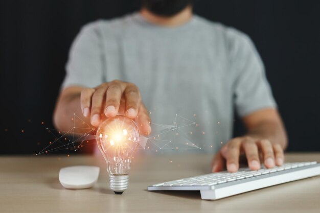 Uomo che tocca le lampadine utilizzando la tastiera del computer. tecnologia di innovazione creativa. creatività pensante, visione del potere e concetto di idee.