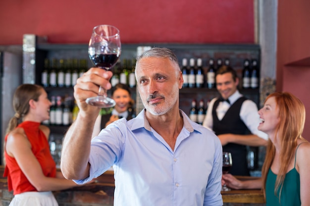 Uomo che tosta con un bicchiere di vino rosso in un bar