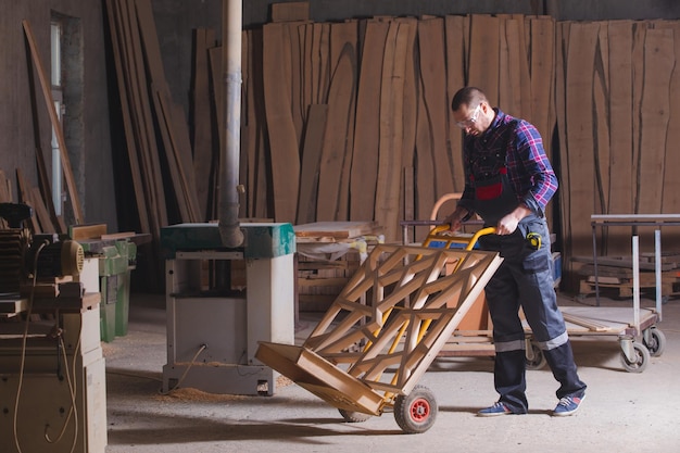 Uomo che trasporta elemento decorativo in legno utilizzando il carrello a mano