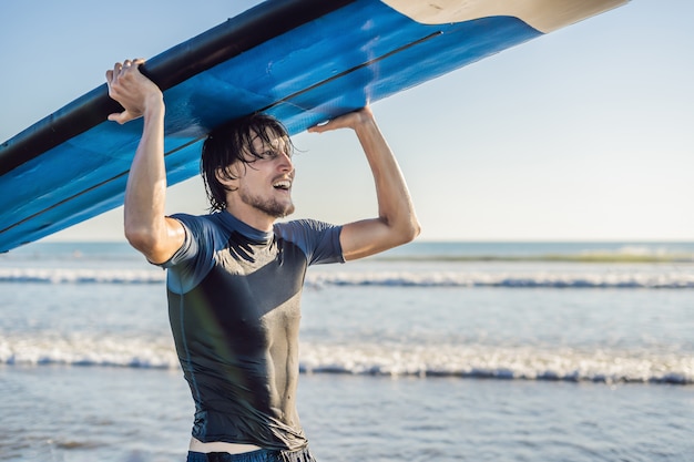 Uomo che trasporta tavola da surf sopra la sua testa