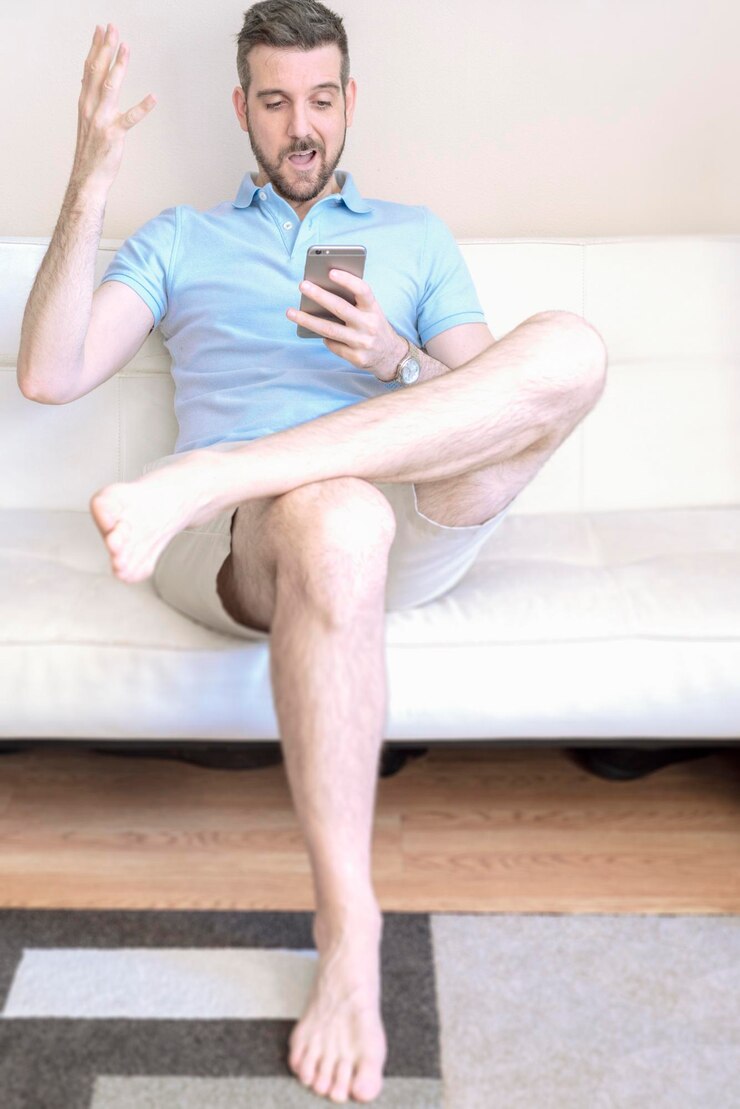 Foto uomo che usa il cellulare seduto sul divano a casa
