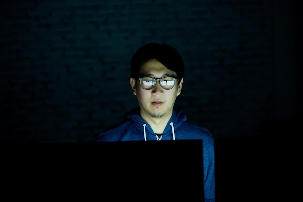 Uomo che usa il computer seduto in camera oscura