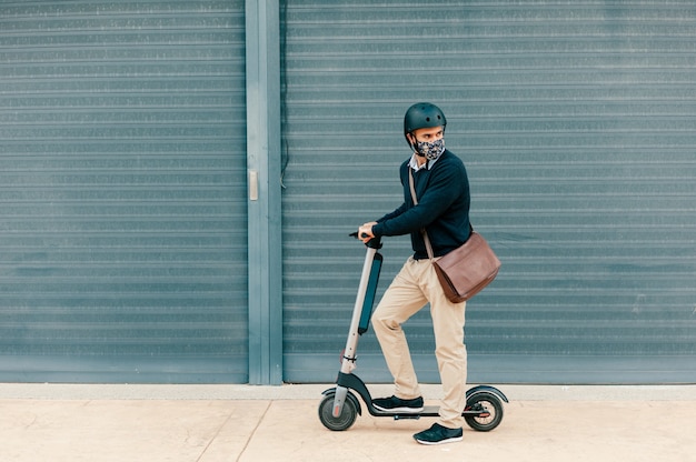 Uomo che usa una maschera chirurgica in sella a uno scooter per lavorare