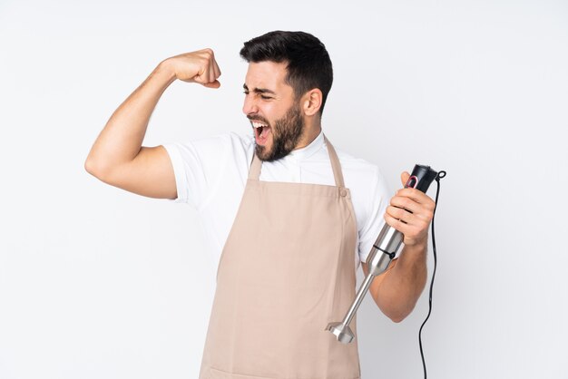 Uomo che usando il frullatore a immersione su bianco che celebra una vittoria