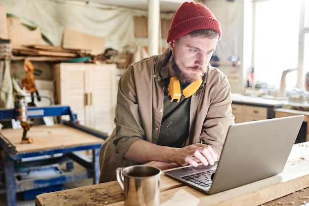 Uomo che utilizza computer portatile in officina