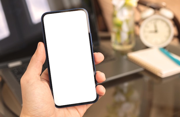 Uomo che utilizza il mockup dello smartphone sullo sfondo dell'interno della casa del laptop con la sveglia e la foto dello spazio della copia della pianta domestica