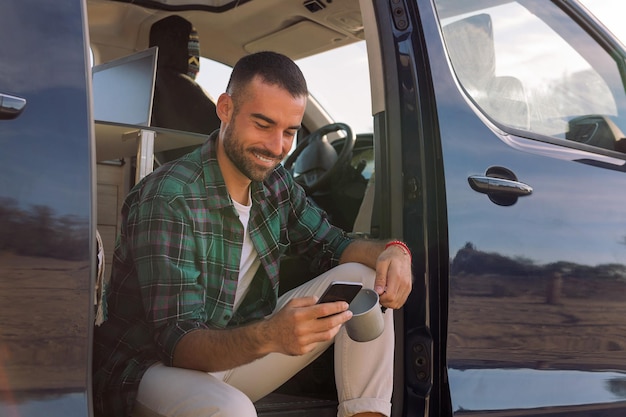 Uomo che utilizza il suo telefono cellulare seduto sul suo camper