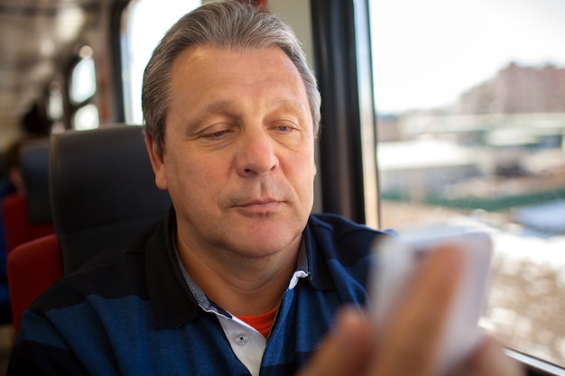 Uomo che utilizza il telefono cellulare durante la corsa in treno