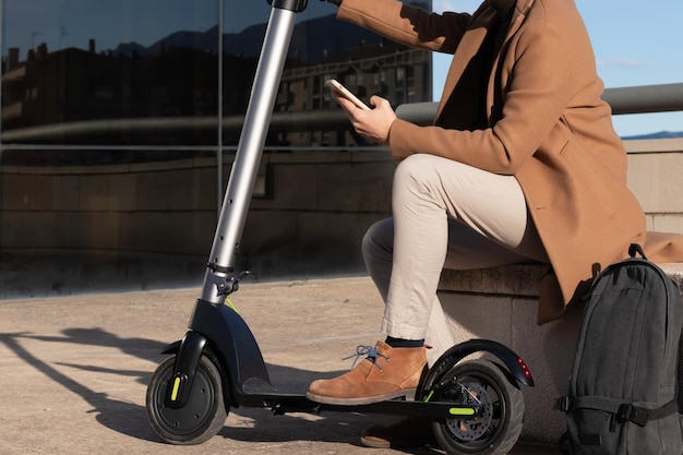 Uomo che utilizza l'app di noleggio smartphone per scooter elettrico in una strada cittadina Tecnologia moderna di trasporto e pendolarismo