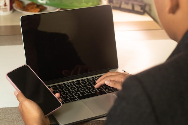 Uomo che utilizza laptop smart phone che lavora a casa