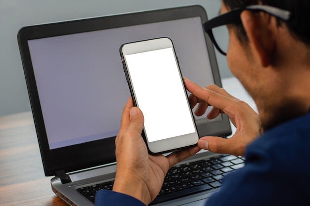 Uomo che utilizza lo smartphone guardando sullo schermo seduto al lavoro d'ufficio