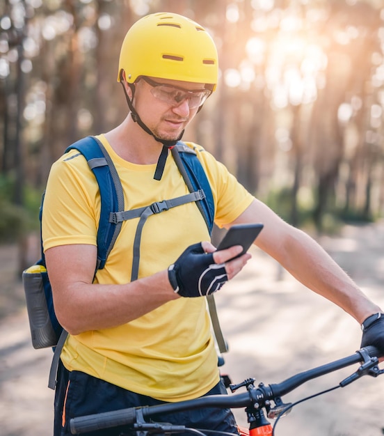 Uomo che utilizza smartphone con mappa durante il ciclismo in legno