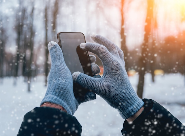 Uomo che utilizza smartphone in inverno con guanti per touch screen