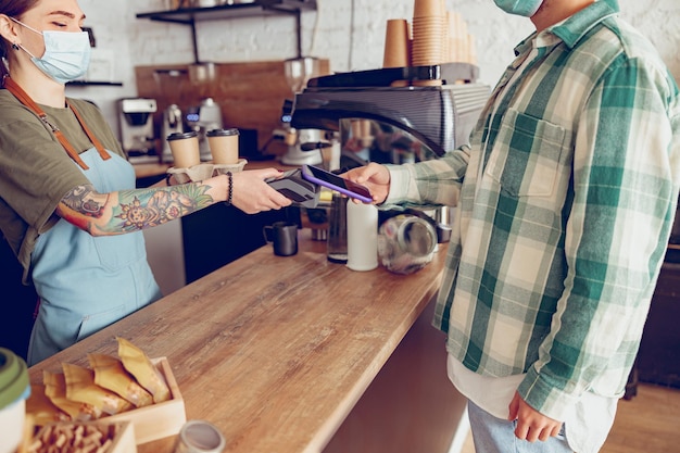 Uomo che utilizza smartphone per pagare il caffè in caffetteria