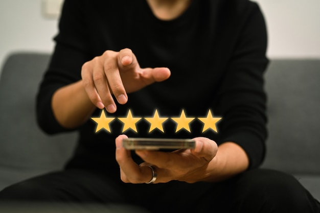 Uomo che utilizza uno smartphone e fornisce sondaggi sulla soddisfazione delle recensioni positive, dando una valutazione a cinque stelle.