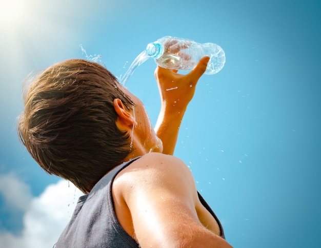 Uomo che versa acqua fresca da una bottiglia sul viso