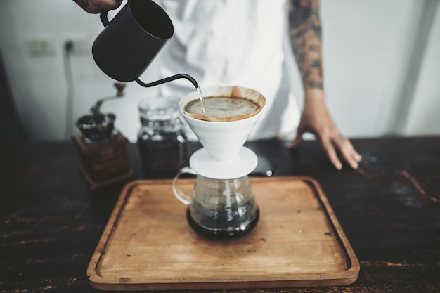 Uomo che versa il caffè in tazza sul tavolo