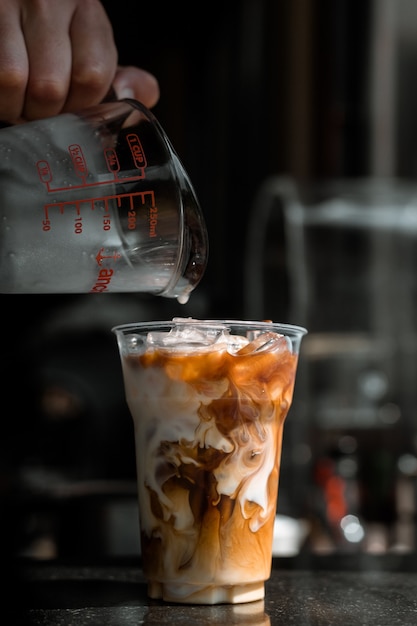 uomo che versa il latte in un bicchiere di caffè freddo