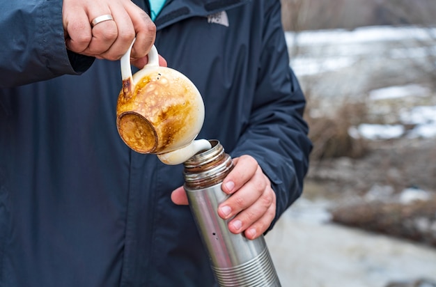 Uomo che versa il tè in un thermos