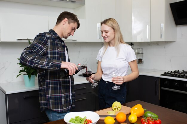 uomo che versa un bicchiere di vino per la sua donna felice in cucina