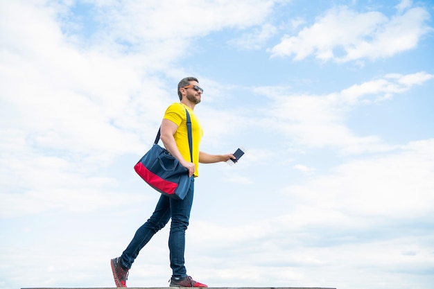 Uomo che viaggia in vacanza con la borsa da viaggio e lo spazio della copia del fondo del cielo del documento