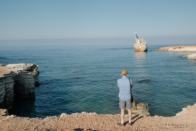 Uomo che viaggia vicino all'oceano a Cipro. Vacanze estive di concetto di stile di vita dell'uomo all'aperto. Bellissimo paesaggio naturale sullo sfondo vista posteriore