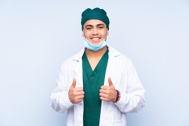 Uomo chirurgo con uniforme isolato su sfondo blu che dà un pollice in alto gesto