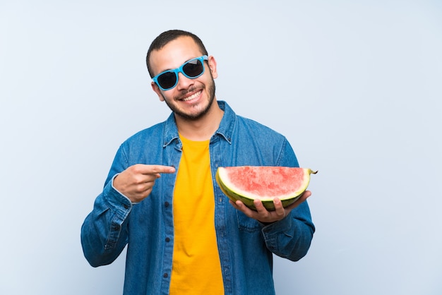 Uomo colombiano che tiene un'anguria sopra la parete blu